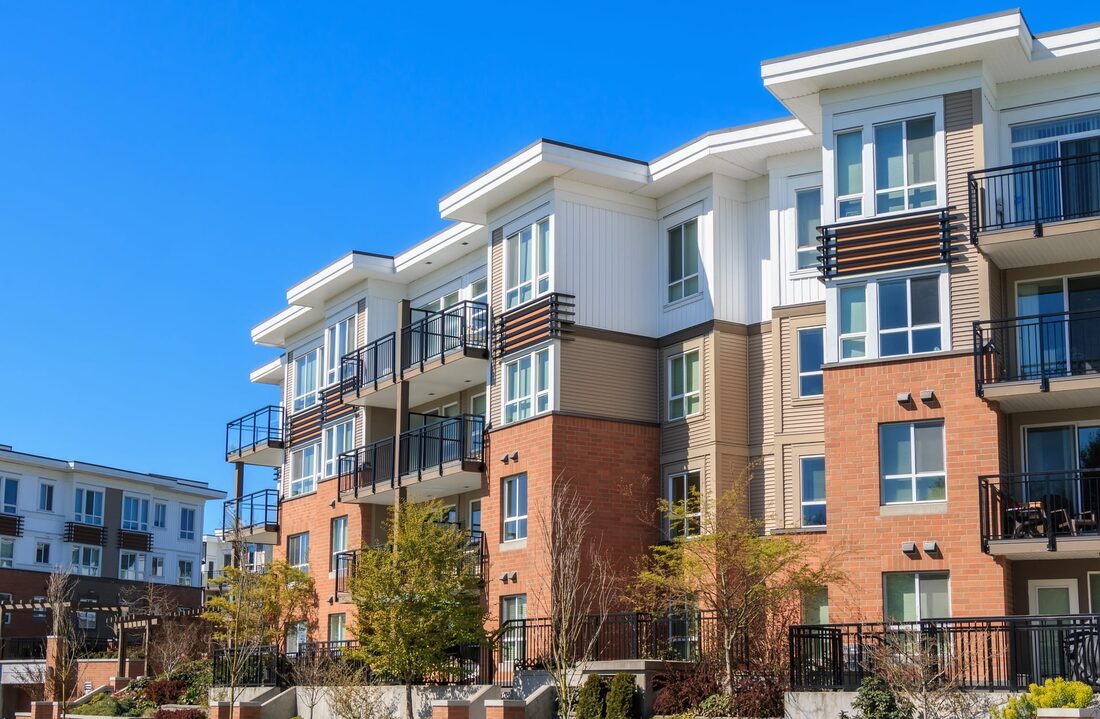 Modern multifamily apartment building with brick and balconies under a clear sky